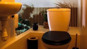 Une salle de bain avec des toilettes, un lavabo et une petite plante en pot.
