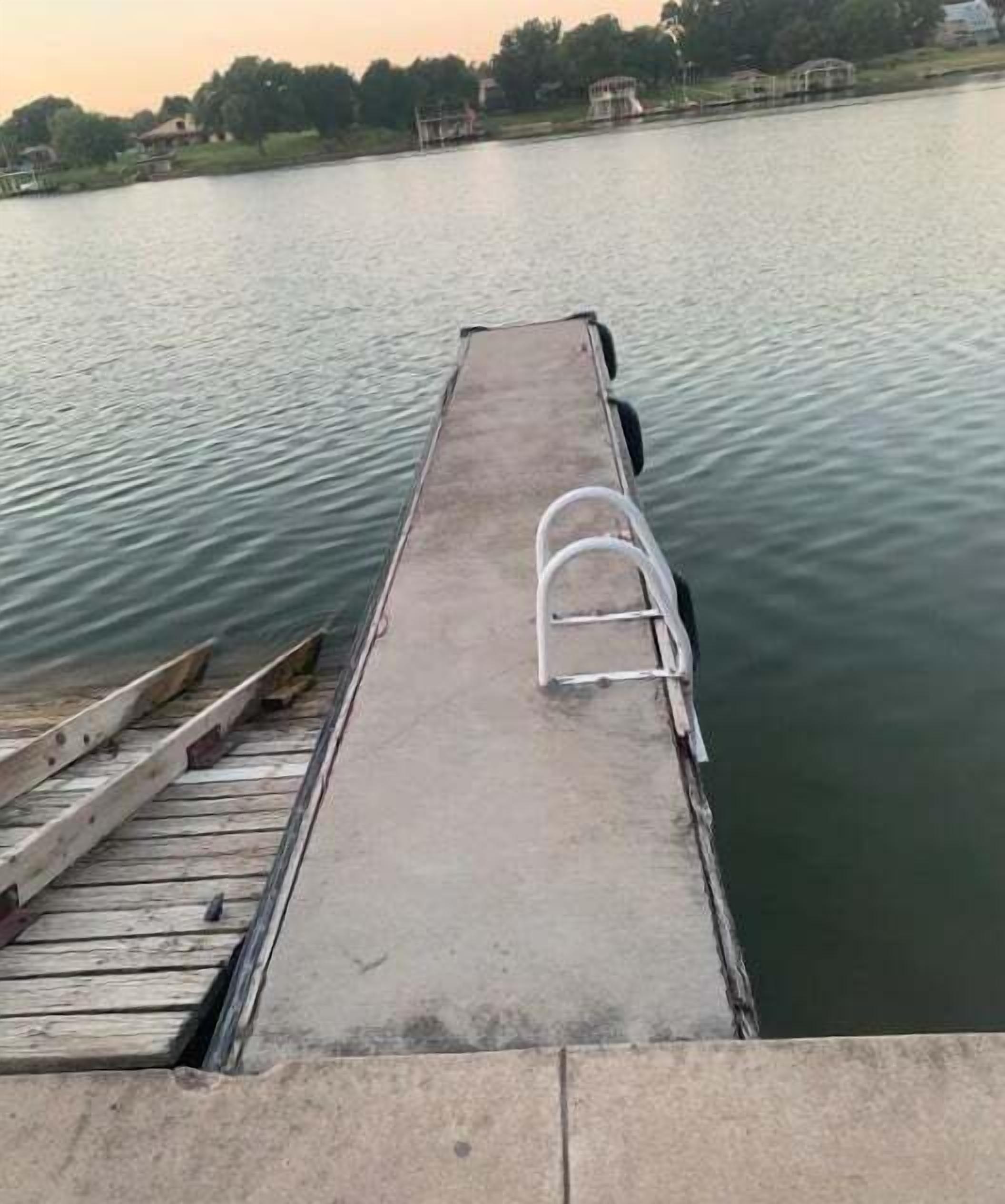 A concrete dock extending into a body of water with a metal ladder on the side.