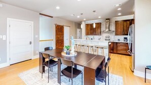 Een moderne keuken met houten kastjes, een roestvrijstalen koelkast en een eethoek met een donker houten tafel en stoelen.