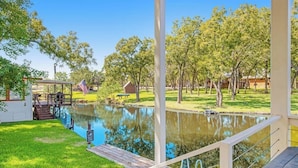 Une piscine dotée d’une terrasse en bois, entourée d’arbres et bordée d’une pelouse.