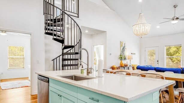Une cuisine dotée d’un îlot central, d’un escalier en colimaçon et d’un coin repas avec un canapé bleu.