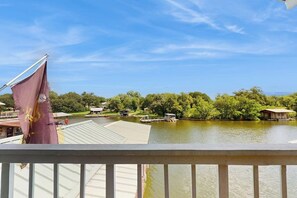 A lakeside view with a dock, boats, and buildings in the background. - Lakefront home on water with great views, boat dock, al fresco dining, and WiFi (Kingsland)