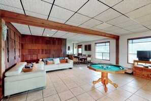A living room with a pool table, a sofa, and a television.