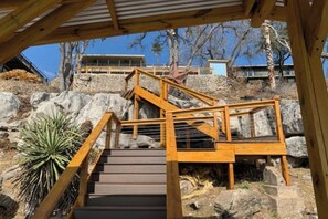 A wooden staircase leading up a rocky hillside with a view of a building in the background.