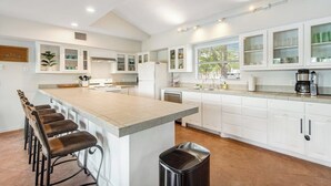 A spacious kitchen with a large island, white cabinetry, and a dining area with bar stools. - Two-story waterfront retreat with boat dock, two firepits & two kayaks (Burnet)