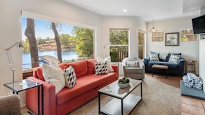 A living room with a red sofa, a grey armchair, a blue sofa, a coffee table, and a TV. - Two-story waterfront retreat with boat dock, two firepits & two kayaks (Burnet)