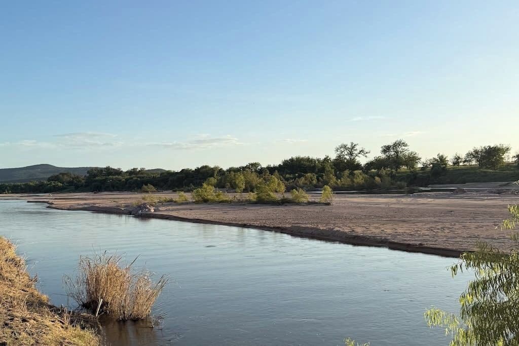 A river with a natural landscape, including trees and hills in the background.