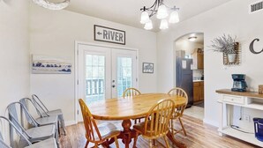 Ein Essbereich mit Holztisch und Stühlen, einer Deckenleuchte und einem Schild mit der Aufschrift 'RIVER'.