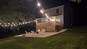 Ein Haus mit Terrasse, Gartenmöbeln und Lichterketten.