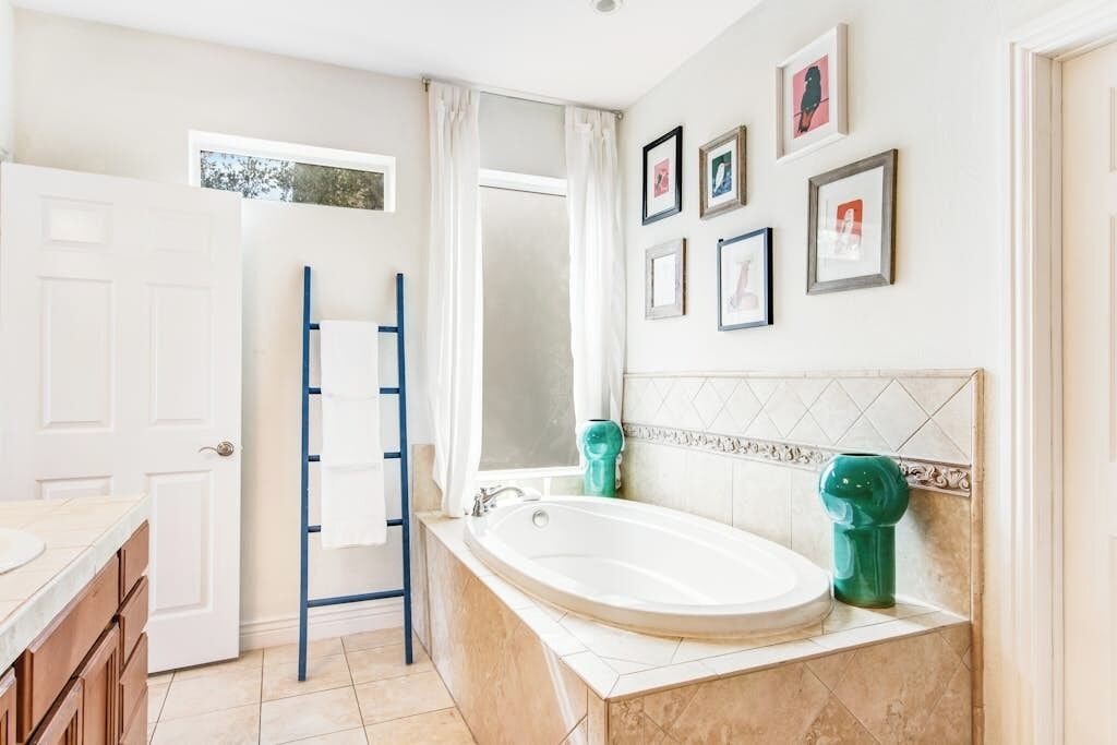 A bathroom with a bathtub, a shower, a towel rack, and framed pictures on the wall.