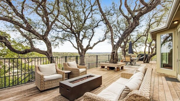A wooden deck with wicker furniture, a fire pit, and a view of the ocean. - Cliffside Oasis | Deck + Dock | Shuffleboard (Spicewood)