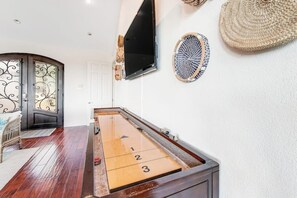 Une table de billard dans une pièce équipée d’un téléviseur, décorée de tableaux et dotée d’un chambranle courbé.