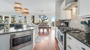 Una cocina moderna con una isla central, electrodomésticos de acero inoxidable y una zona de comedor con vistas.