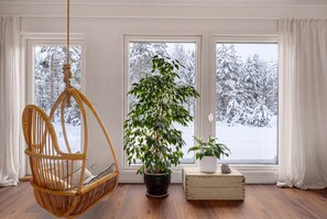 A room with a hanging chair, a potted plant, and a wooden chest. - Villa Arctic Glow with Sauna (Rovaniemi)