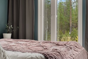 A bedroom with a bed, curtains, a window, and a plant. - Villa Arctic Glow with Sauna (Rovaniemi)