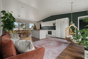 Une cuisine moderne avec des meubles blancs et un fauteuil suspendu.