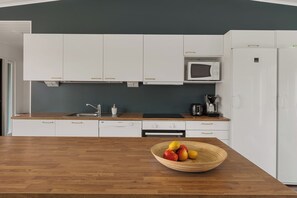 A modern kitchen with white cabinets, a microwave, a coffee maker, and a fruit bowl on the counter. - Villa Arctic Glow with Sauna (Rovaniemi)