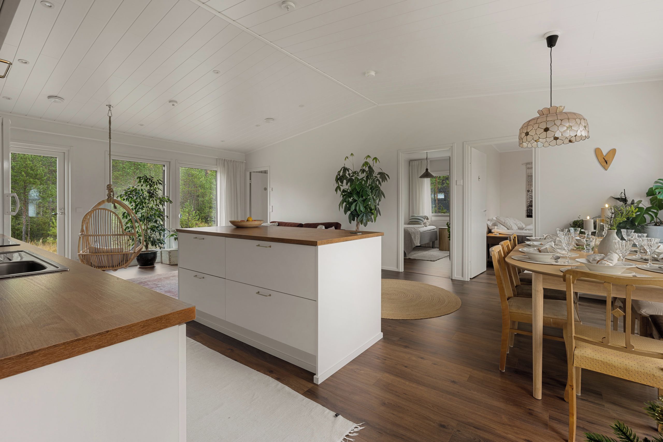 A spacious kitchen with a wooden island, a dining area with a round table, and a view of the outdoors.