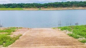 A concrete pathway leading to a body of water with a forested area in the background.