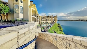 Ein Hotel mit Pool, einer Steintreppe und Blick auf das Wasser.