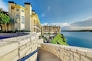 A hotel with a pool, a stone staircase, and a view of the water. - Lavish lakefront retreat in private island community with pools, tennis, & gym (Lago Vista)
