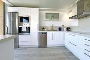 A modern kitchen with stainless steel appliances, white cabinetry, and a built-in microwave. - Private Pool Villa in Salobre Golf (Maspalomas)