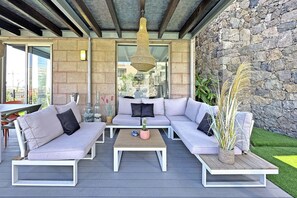 A modern outdoor seating area with a stone wall, a hanging light fixture, and a potted plant. - Private Pool Villa in Salobre Golf (Maspalomas)