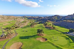 A golf course with a clear view of the ocean, palm trees, and distant buildings. - Private Pool Villa in Salobre Golf (Maspalomas)