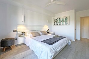 A modern bedroom with a large bed, bedside tables, a ceiling fan, and a wall-mounted artwork. - Private Pool Villa in Salobre Golf (Maspalomas)