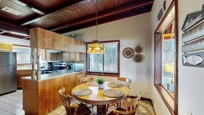 Une cuisine avec des meubles en bois, un îlot central et un coin repas comprenant une table ronde et des chaises.