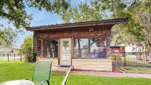Un petit bâtiment en bois doté de grandes fenêtres, d’une porte et d’un petit espace porche.