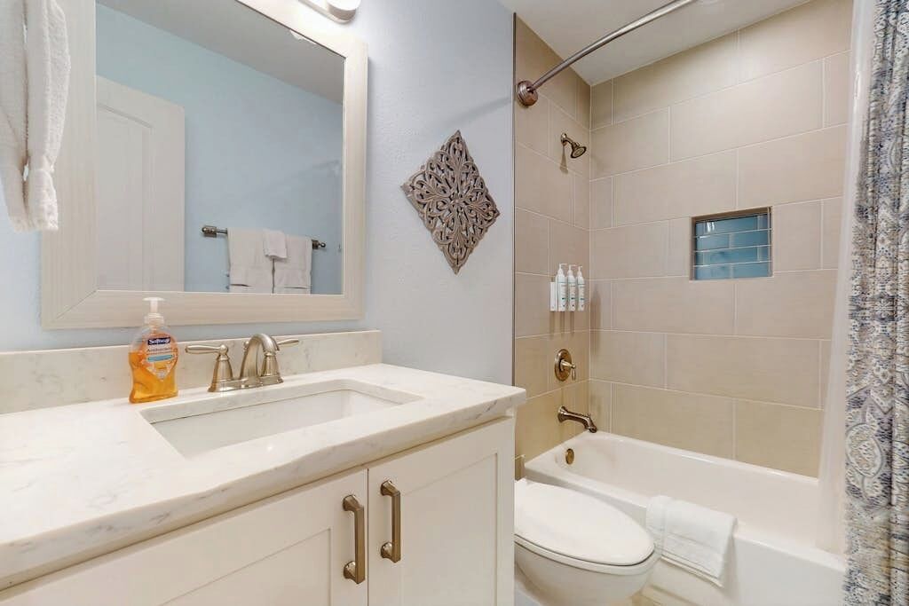 Une salle de bain équipée d’un lavabo, d’un miroir, d’un meuble-lavabo et d’une baignoire.