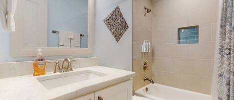 Une salle de bain équipée d’un lavabo, d’un miroir, d’un meuble-lavabo et d’une baignoire.
