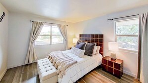 A bedroom with a bed, bedside tables, a headboard, and windows.