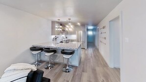 A modern kitchen with a central island, bar stools, and stainless steel appliances.