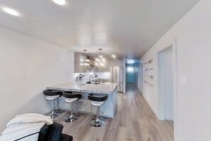 Eine moderne Küche mit einer zentralen Kochinsel, Barhocker und Edelstahlgeräten.