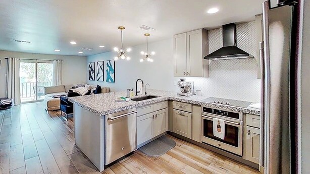 A modern kitchen with a central island, stainless steel appliances, and pendant lighting.