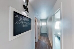 Ein Flur mit einer Tafel an der Wand, Holzdielen und weißen Wänden.