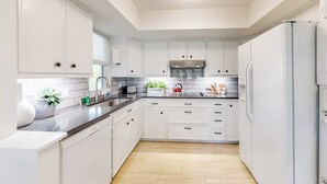 Una cucina moderna con mobili bianchi, un lavello in acciaio inossidabile e un forno a incasso.