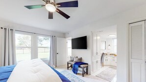 Una camera da letto con un letto, una scrivania, una sedia, una televisione e una ventola a soffitto.