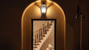 An arched doorway leading to a staircase with a white statue, a wall-mounted light, and a bell. - Vigne Franceschini Resort - villa with pool in the heart of Rome (Roma)