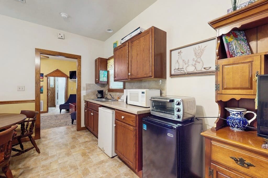 Cocina compacta con armarios de madera, refrigerador, microondas y tostadora.