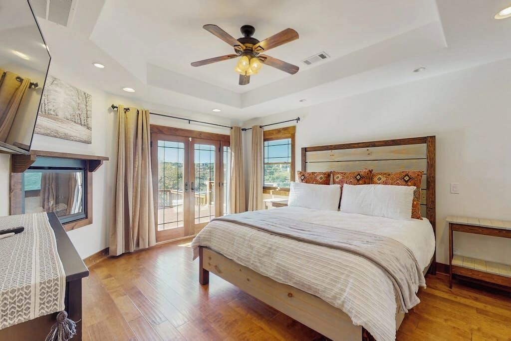 Une chambre à coucher avec un lit, un ventilateur de plafond, une fenêtre et une vue sur l’extérieur.