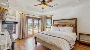 Un dormitorio con cama, ventilador de techo, ventana y vistas al exterior.