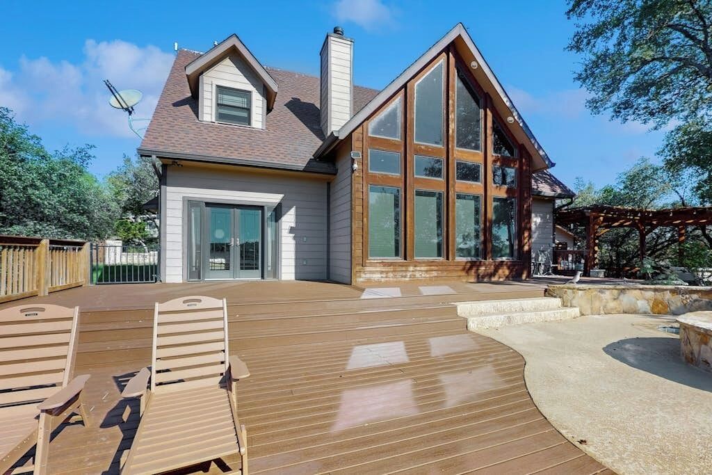 Une maison dotée d’une grande terrasse, d’une cheminée et d’une pergola.