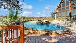 Una piscina con cubierta de madera, una estructura de piedra y un edificio con grandes ventanales.