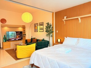 Une chambre moderne avec un lit, un canapé, une télévision et un panneau mural en bois.