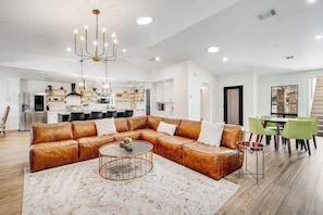A spacious living area with a leather sectional sofa, a round coffee table, and a chandelier. - Spacious & elegant haven with huge yard, updated interior, AC, & fast WiFi (Horseshoe Bay)
