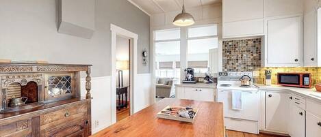 Una cocina con armarios blancos, una isla de madera y un ventanal.