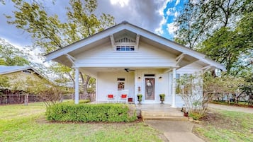 Ein eingeschossiges Haus mit Veranda, Garage und gepflegtem Rasen.